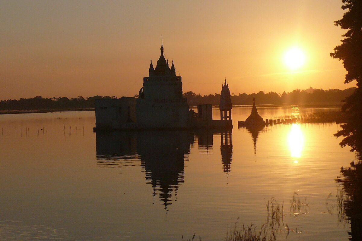 Templo birmano reflejado en el agua al atardecer, en Myanmar
